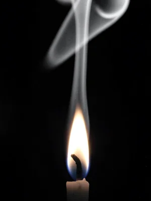 A candle flame centered in frame with rising column of heat shimmer visible abov