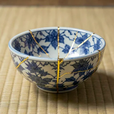 Repaired blue-and-white bowl on tatami mat — crack pattern visible against ceram
