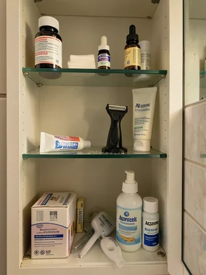 The interior of a medicine cabinet in morning light, three glass shelves holding