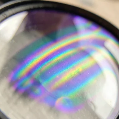 Anti-reflective coating on camera lens, deep purple-green interference sheen on 