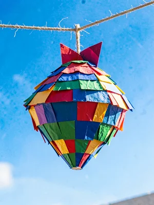 A seven-pointed piñata hanging from a cord against a bright blue sky