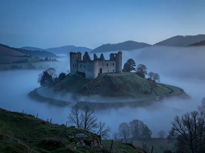 Castle ruin on hill surrounded by fog moat