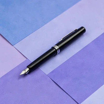 Color-block hero of a single fountain pen lying diagonally on a periwinkle color