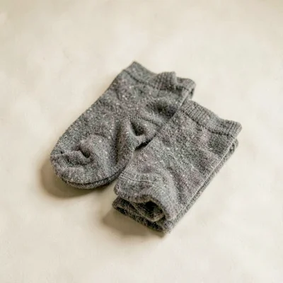 Lightbox shot of a single pair of folded wool socks on a soft cream backdrop, ge
