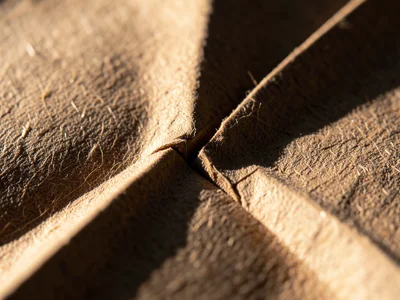 Paper grain direction fighting a fold, fibers cracking slightly where fold cross