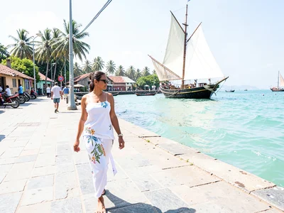 Brilliant Indian Ocean noon light in Dar es Salaam, Woman in white kanga walking