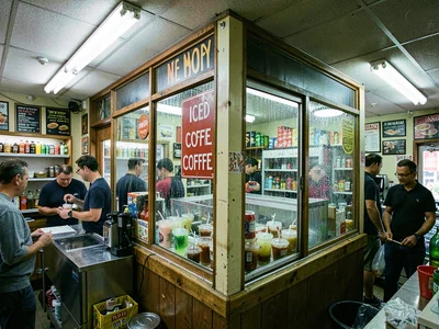 Iced coffee sign in summer window, sweating drinks in cooler visible