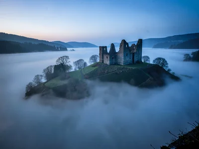 Castle ruin on hill surrounded by fog moat