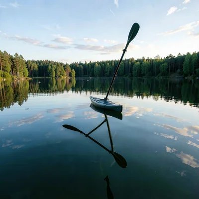 Finnish lake mirror, dead-calm reflection, Kayak paddle raised mid-stroke, refle