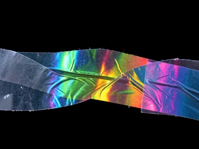A strip of clear packing tape stuck to glass under cross-polarized light, the ta
