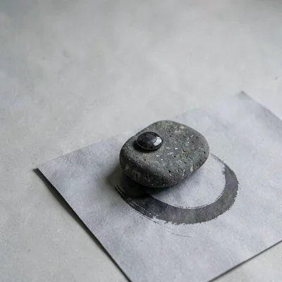 One worn ink stone resting on cool-grey paper, surface bearing a polished cresce