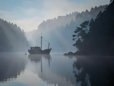 Fishing boat becoming silhouette in mist