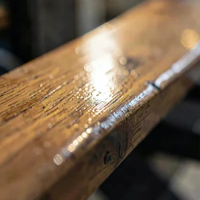 Tight crop of a long bench plank polished by use, warm directional light