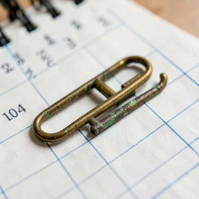 Mineral close-up of a brass paperclip on a planner page, oxidized patina along t