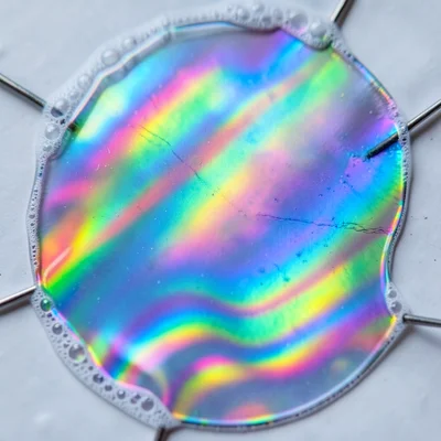Soap film in extreme cold, thickening as it chills, broad saturated color bands 