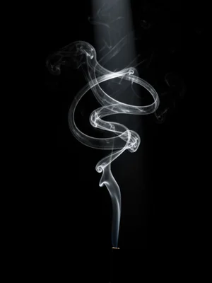 Incense smoke trail forming perfect spiral, backlit, dark room, single beam of l