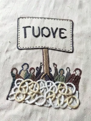 A protest sign held aloft reading a single word, the crowd blurred into French k