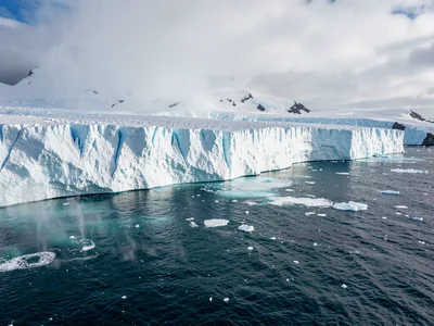 Glacier calving moment in full panoramic context, scale of ice meeting scale of 