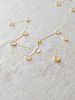 Glue-spot raised constellation across vellum in small clear domes catching tiny
