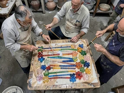 Glass rod cane pulling moment — two workers stretching molten bundle, workshop b