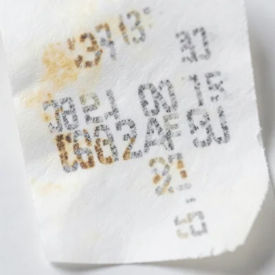 Close-up of thermal paper showing partial fade, individual characters dissolving