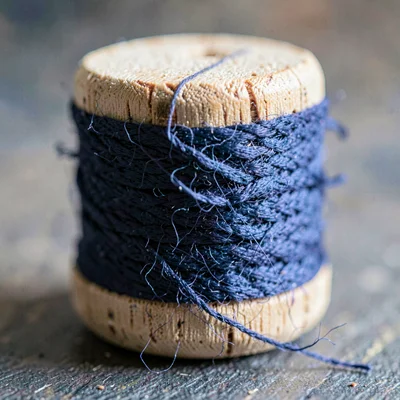 Mineral macro of a wooden bobbin wound with deep indigo wool