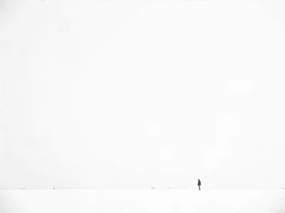 Lone figure tiny in snow vastness