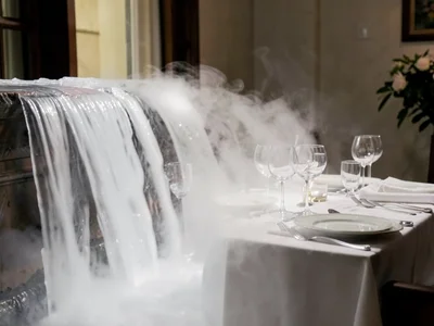Dry ice fog flowing over table edge like waterfall, dinner table setting