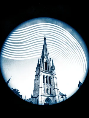 A city cathedral spire — seasonal sun arcs curving above the stonework