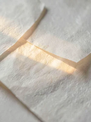 Layered-paste lift on rice paper exposing translucent underlayer where warm ligh