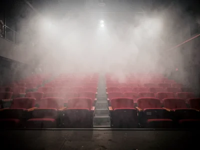 Fog machine output in empty theater, rows of red seats disappearing into mist