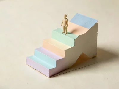 A papercraft staircase rising from a flat cream floor, every step a different so