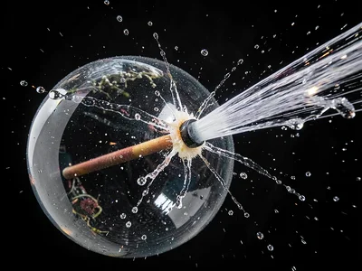 Water-filled balloon hit by dart with puncture point and emerging water jet visi