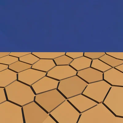 Polygonal mud-cracks tile an ochre dry wash under a deep lapis sky, hard mid-day