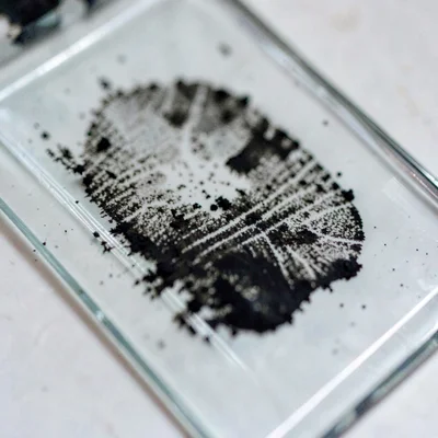 Mineral close-up of dried ink residue on a glass slab, dark with fingerprint smu