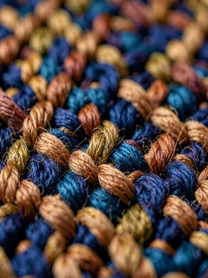 Macro of one-centimeter walnut-brown wool warp shows fiber twist and dye-irregul