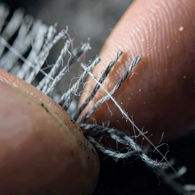 Macro of fringe trim threads parted by a finger, deep shadows between strands