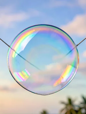 Single soap film stretched across a thin wire ring catching every color of the v