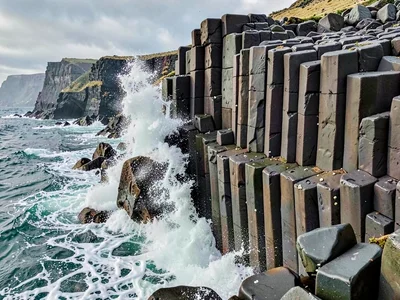 Wave crashing against columnar basalt cliff