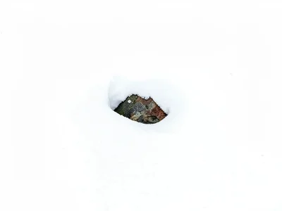 Single stone emerging from snow drift