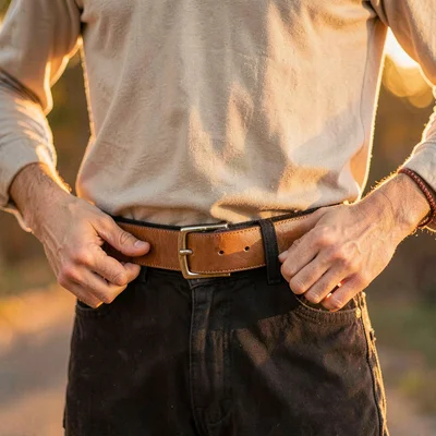 Warm vertical of a model fastening a belt at the waist, golden hour glow on the 
