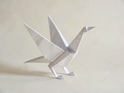 A delicate origami paper crane stands poised showing crisp folded wings and a sl