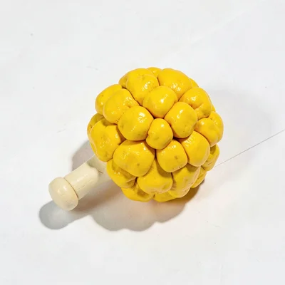 Spirited chunky clay pom-pom in primary yellow with stubby cream-toned handle an
