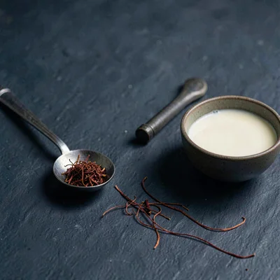 Moody still life of a tasting spoon with a few threads of saffron beside a small