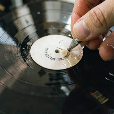 Macro of a stamped center label being applied wet to a fresh LP, fiber grain