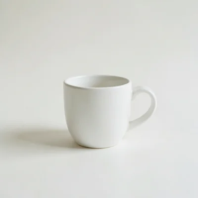 Minimalist photography of a single white coffee cup centered on a clean off-white background, soft natural side light, s