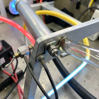 Close-up of the metal backplate clips holding a glass tube to an aluminum frame