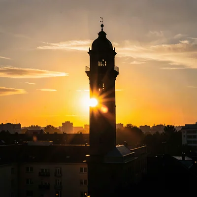 Water tower silhouetted against amber and gold sunset