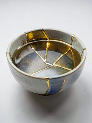 Repaired bowl filled with water — gold lines reflected in still surface