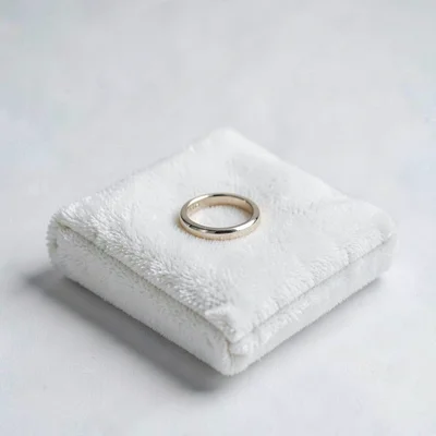Clean studio shot of a single ring on a folded white velvet pad, soft shadow